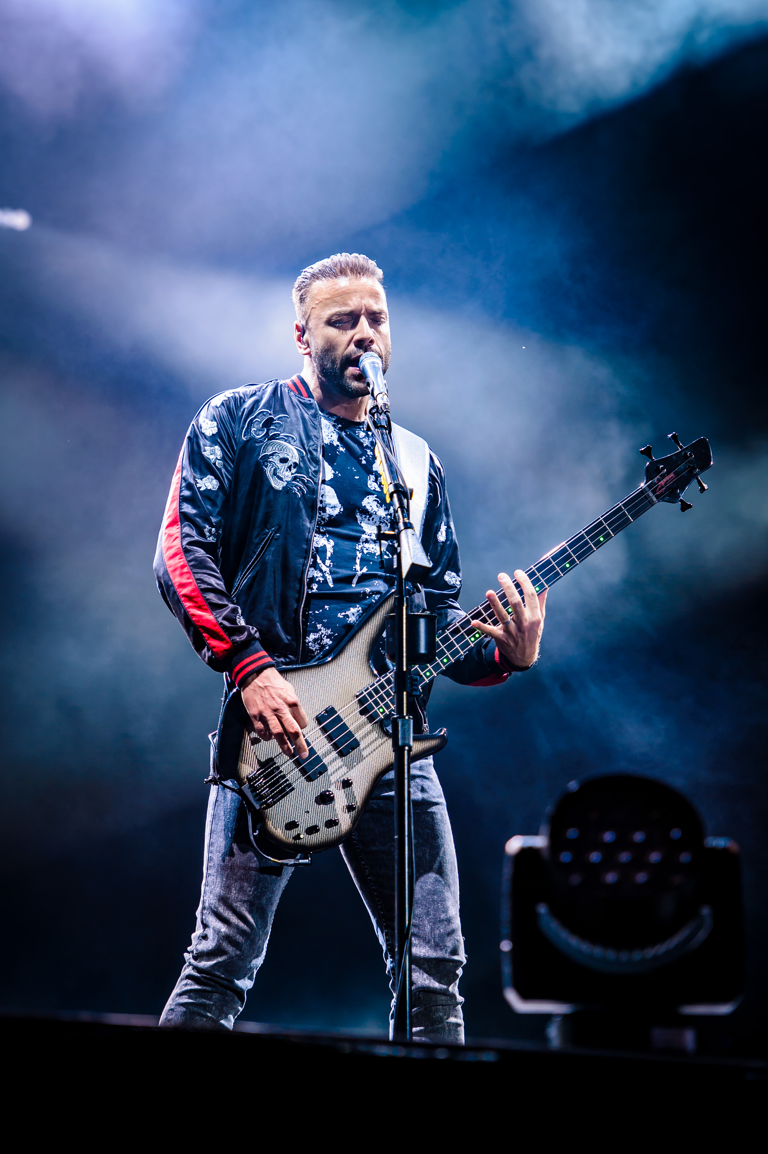 Chris Wolstenholme on stage singing and playing bass guitar